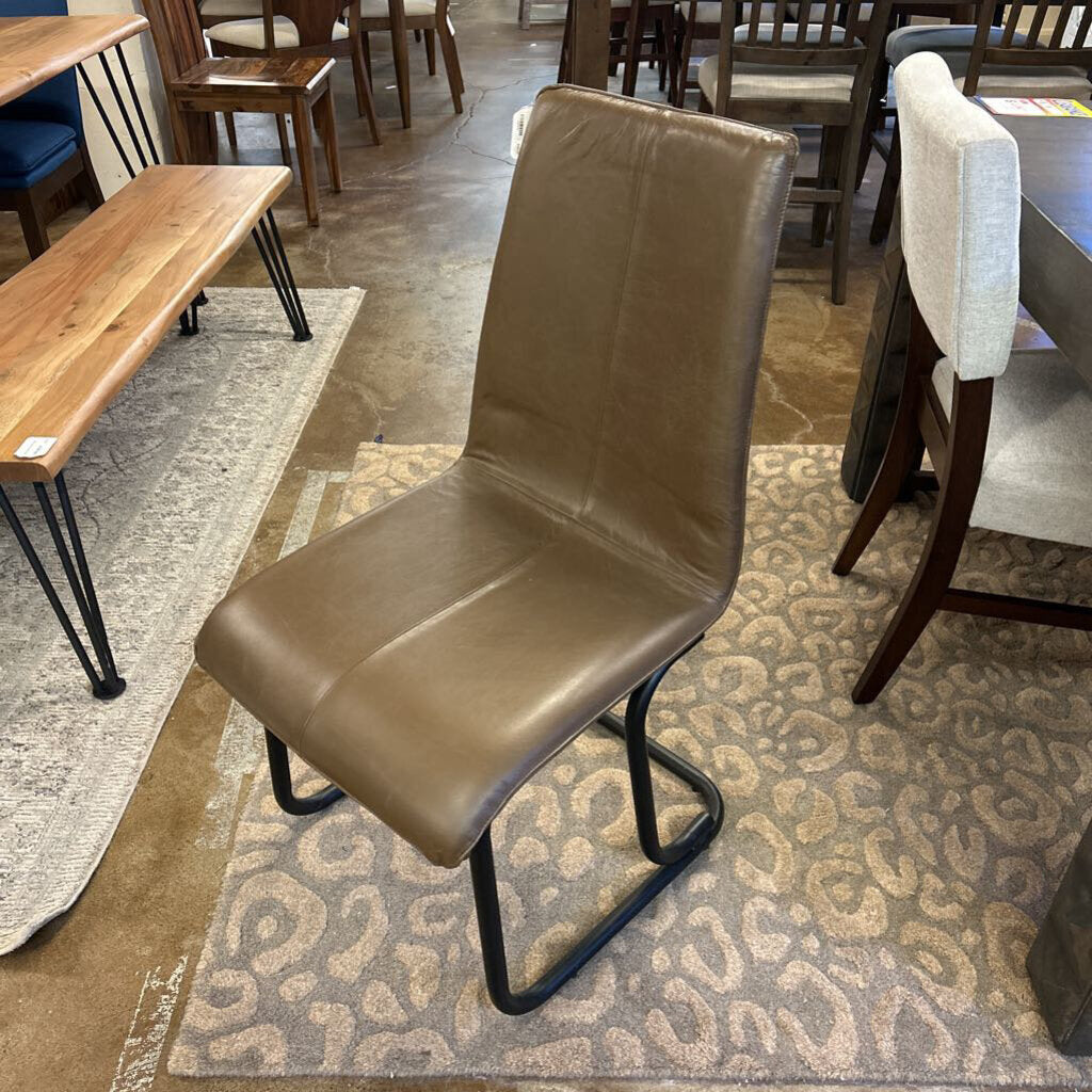 Brown chair on a patterned rug in a room with tables and chairs.
