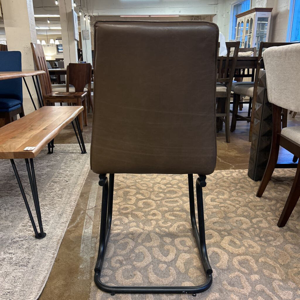Brown chair with black legs on a patterned rug in a furniture store