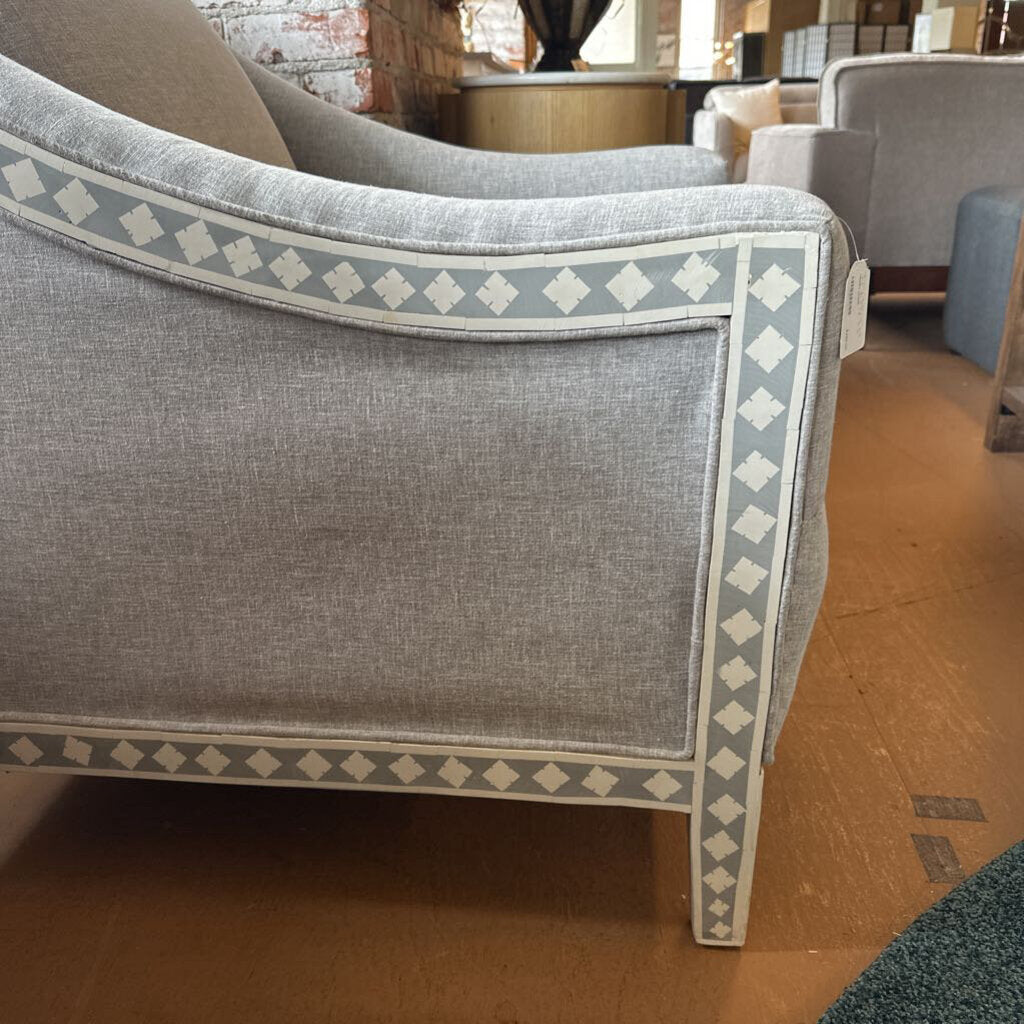 Gray armchair with decorative pattern on a wooden floor
