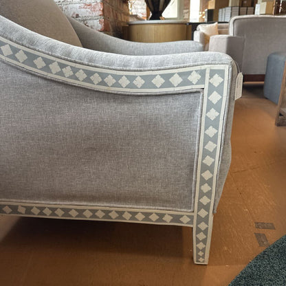 Gray armchair with decorative pattern on a wooden floor