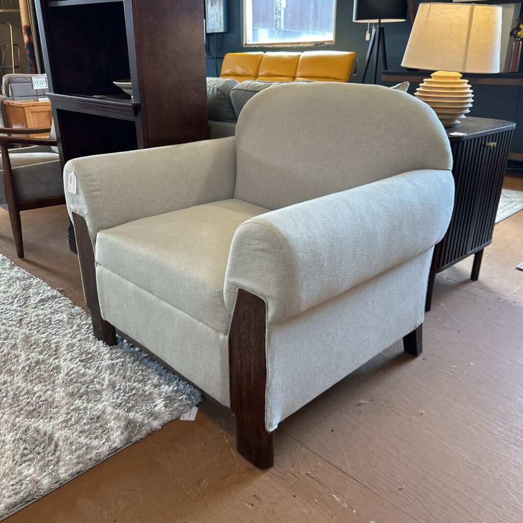 Beige armchair in a living room setting with a yellow sofa and wooden coffee table.