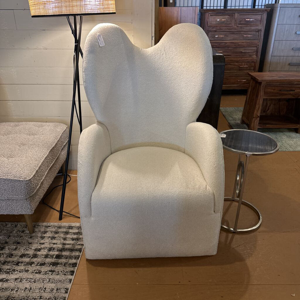 White armchair in a room with wooden furniture and a lamp.