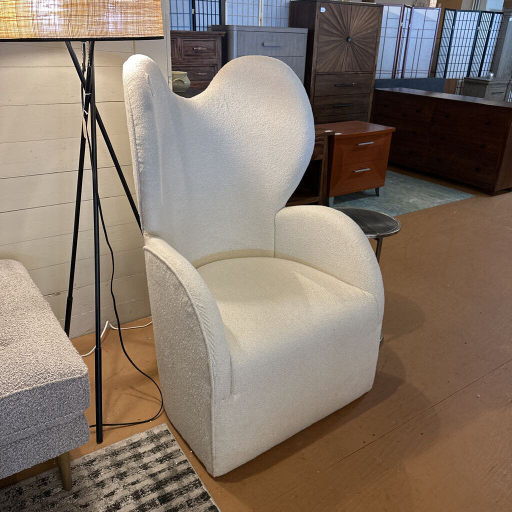 White armchair in a room with wooden flooring and furniture.