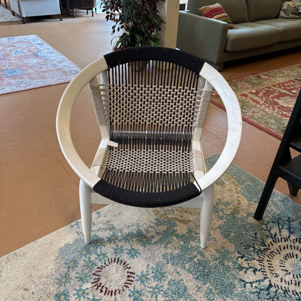 Chair with woven backrest and white frame on a patterned rug
