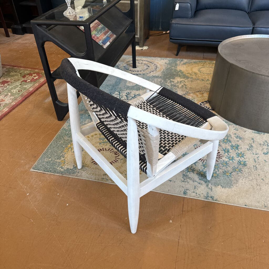 White chair with black woven backrest on a patterned rug in a living room setting