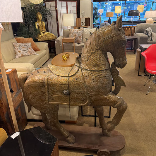 This monumental Indian-style Ashva horse statue is a masterwork of decorative craftsmanship, designed to serve as a grand focal point in a high-end interior. The statue is finished in a highly detailed antiqued brass or bronze-toned metal, featuring intricate embossed patterns that mimic traditional ceremonial armor and tack.