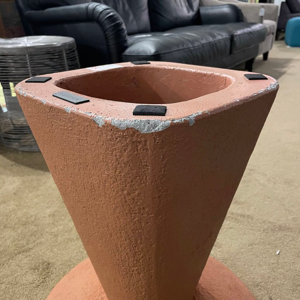 bottom view of a pale orange concrete table showing light damage to the paint