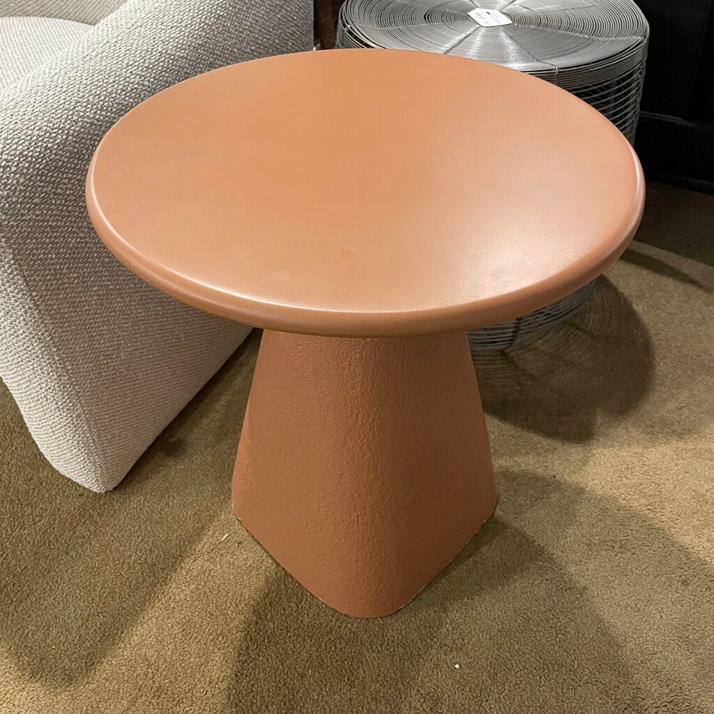 Round pale orange concrete table on a carpeted floor 
