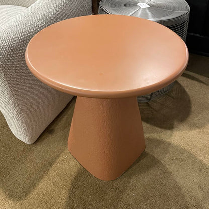Round pale orange concrete table on a carpeted floor 