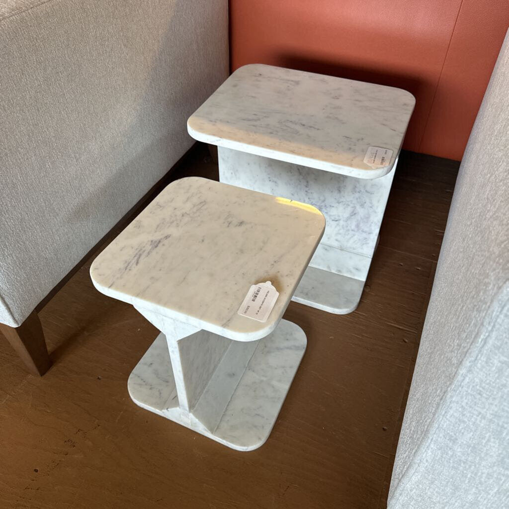 Two small wooden tables with beige tops against a wall.