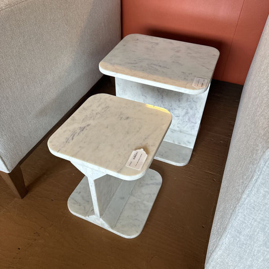 Two small wooden tables with beige tops against a wall.