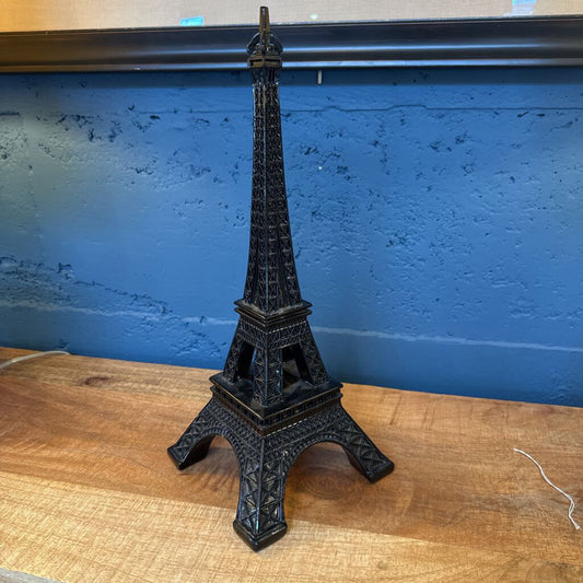 Black Eiffel Tower model on a wooden surface with a blue wall background