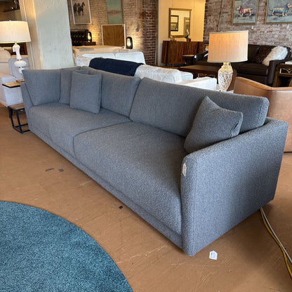 Gray sofa with cushions on a cardboard floor in a showroom setting
