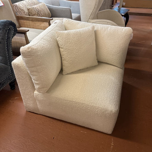 Beige armchair with cushions in a room with wooden flooring and other furniture.