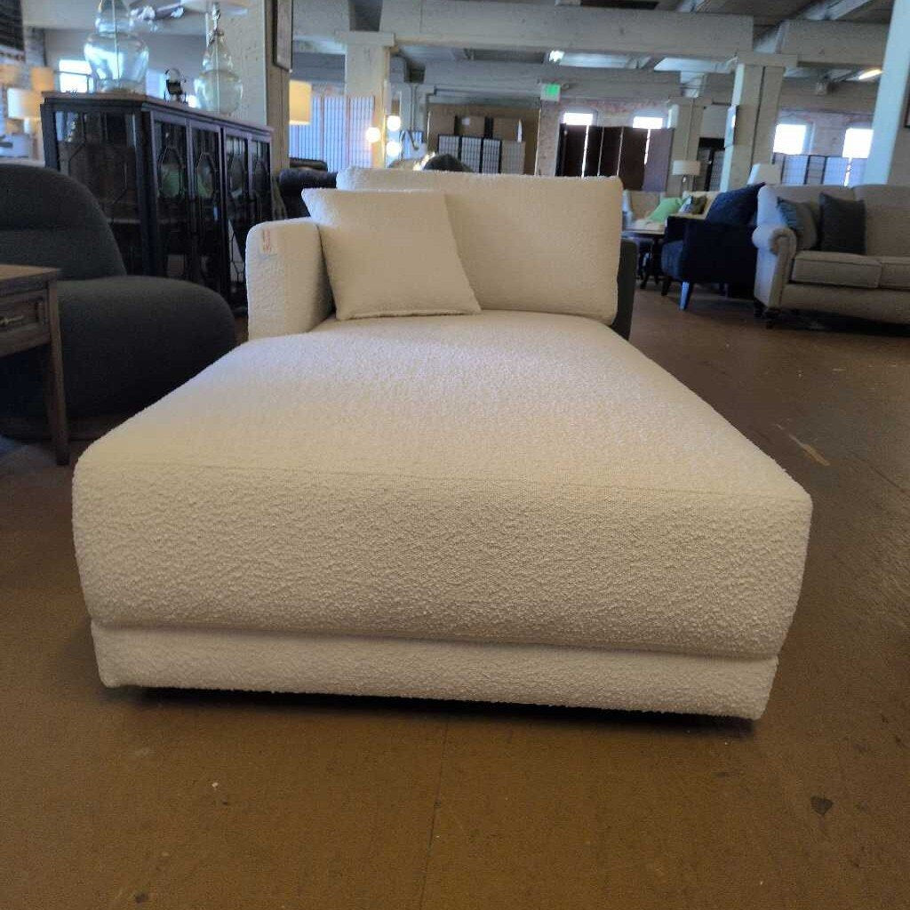 White textured chaise lounge in a showroom setting with other furniture.