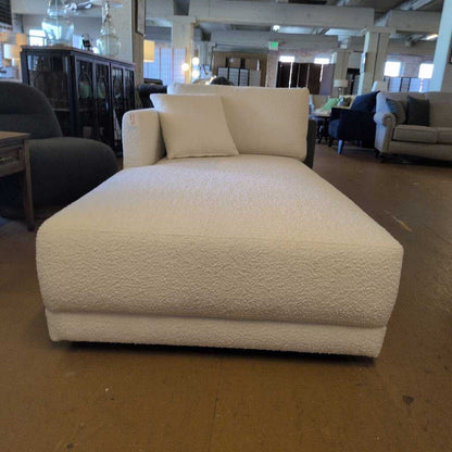 White textured chaise lounge in a showroom setting with other furniture.