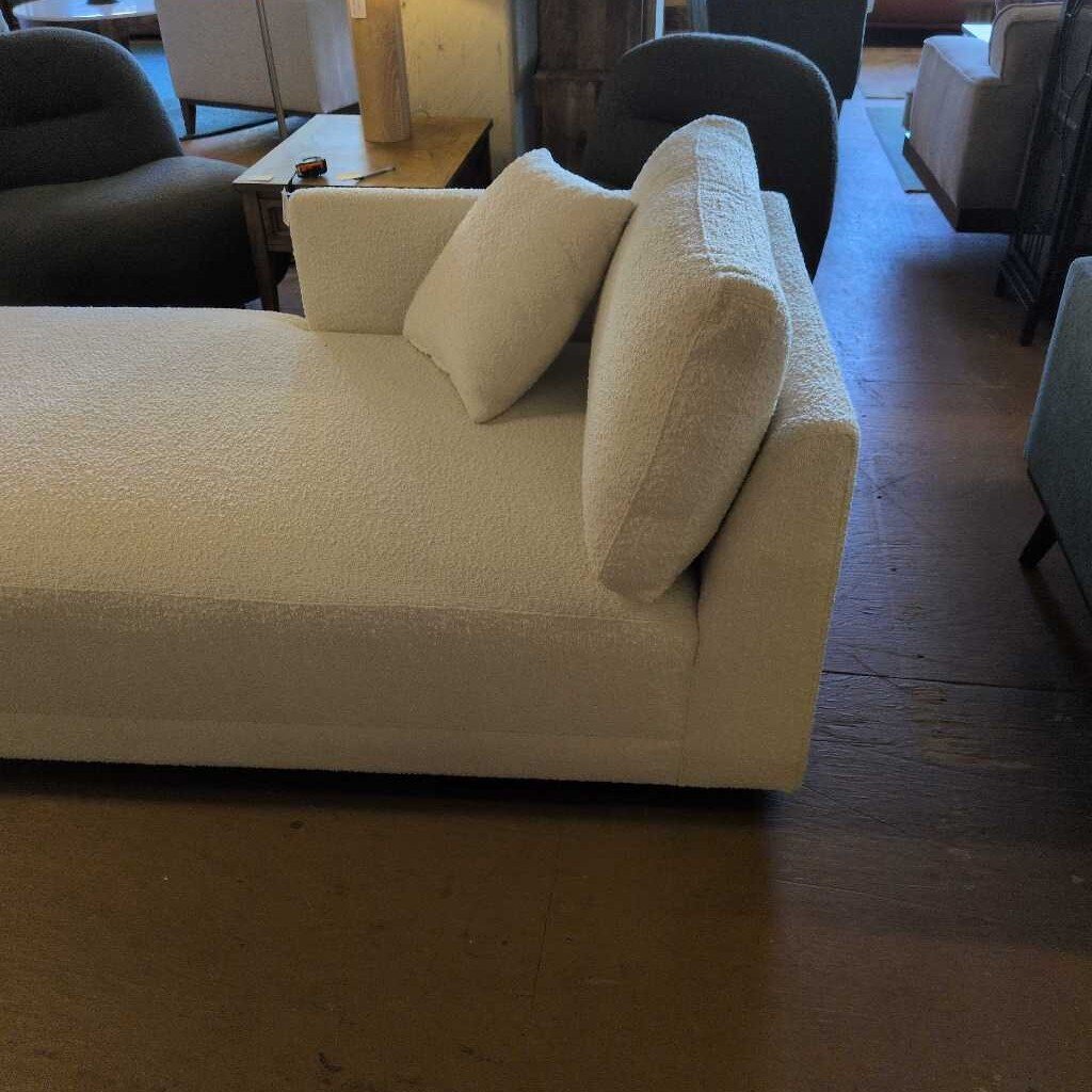 Beige sofa with cushions in a room with wooden flooring and chairs.