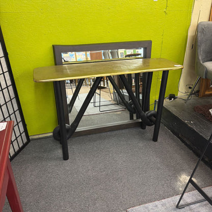 Wooden table with black metal legs against a green wall