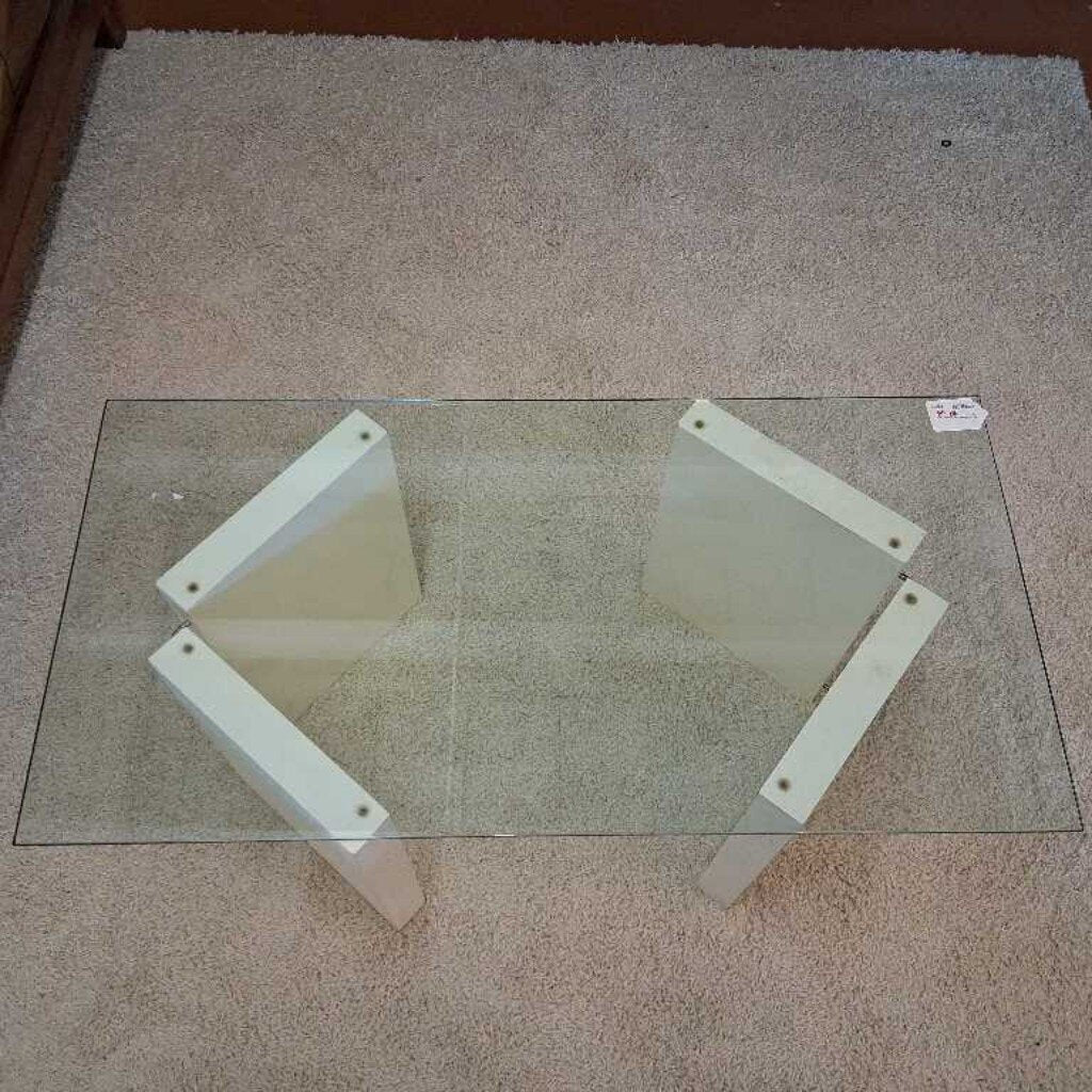 Glass table with white metal legs on a carpeted floor