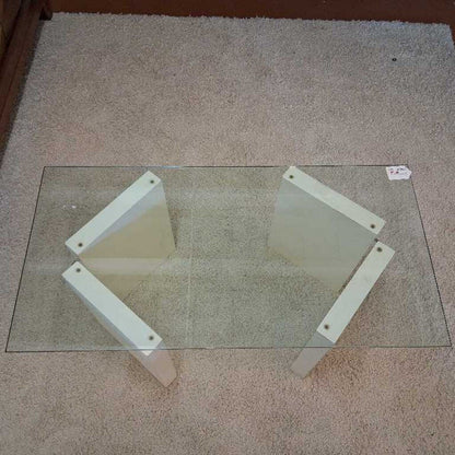 Glass table with white metal legs on a carpeted floor