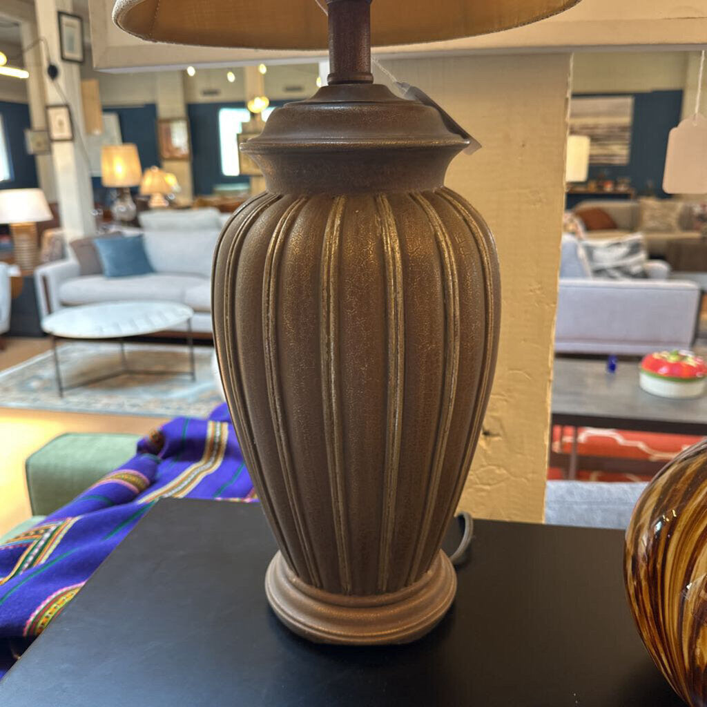 Decorative lamp with a ribbed design on a table in a room with furniture and decor.