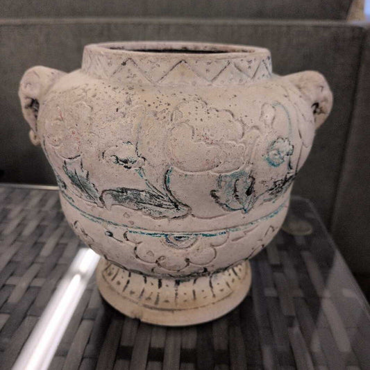 Decorative ceramic vase with intricate patterns on a metal surface