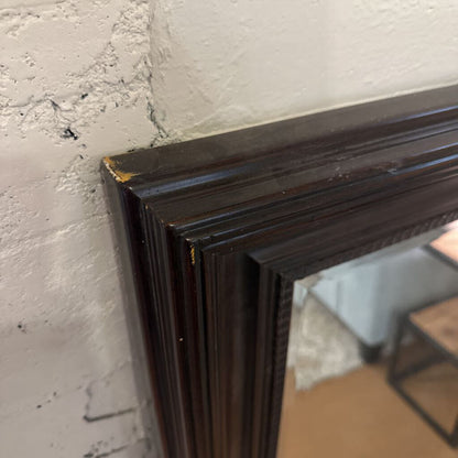 Close-up of a dark wooden picture frame corner against a textured wall.