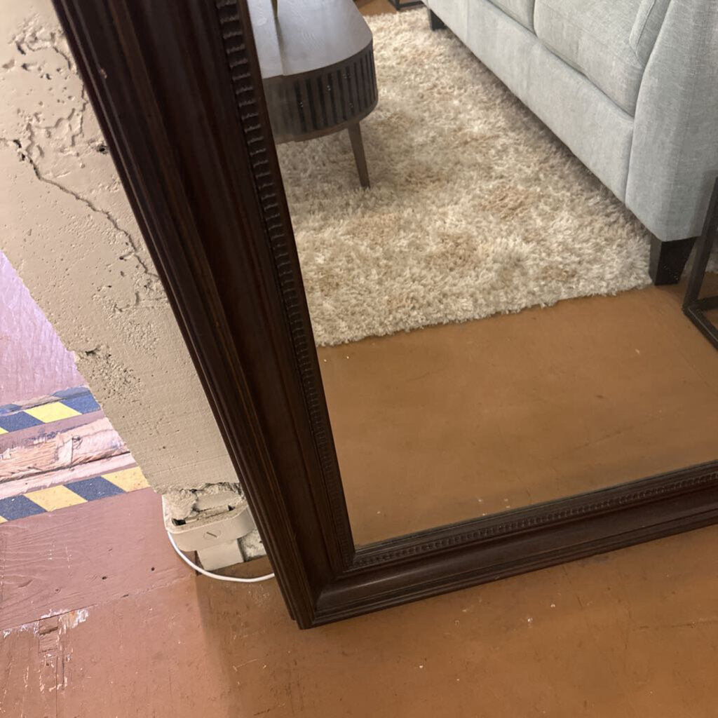 Large floor mirror with a dark wooden frame on a wooden floor.