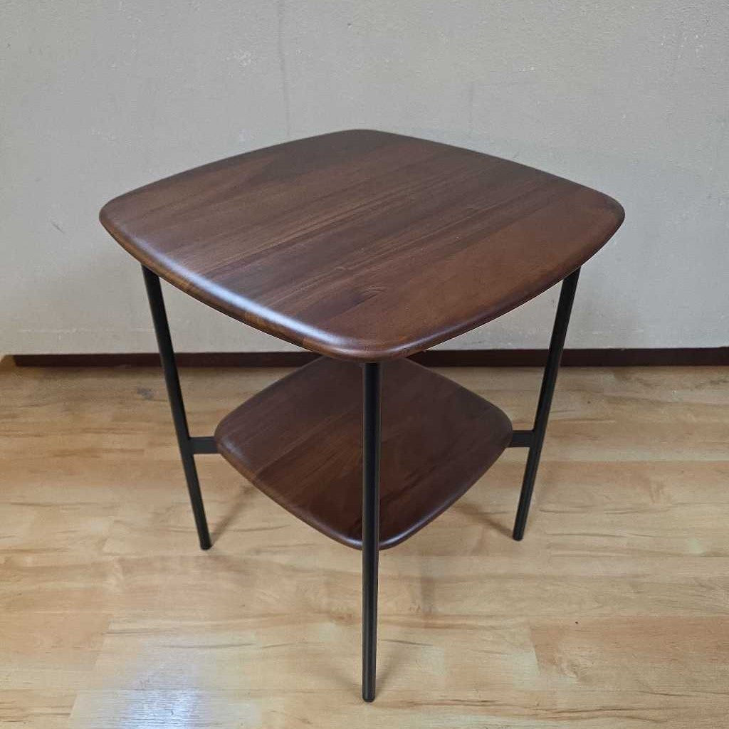 Wooden side table with a single shelf on a wooden floor.