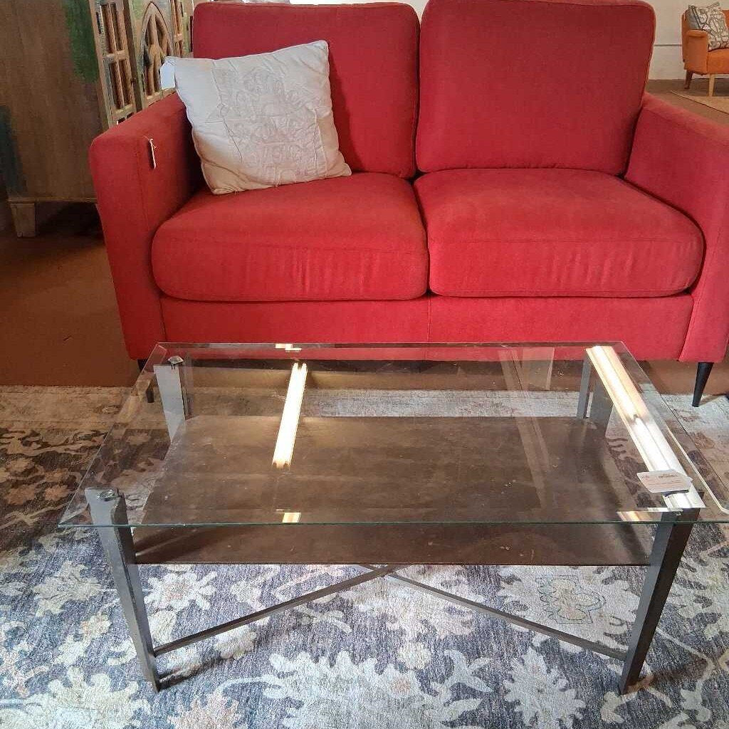 Red sofa with a glass coffee table on a patterned rug