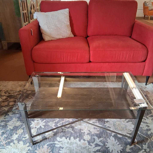 Red sofa with a glass coffee table on a patterned rug