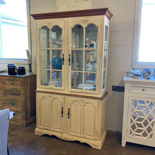 Beige glass-fronted cabinet with wooden trim in a room setting.