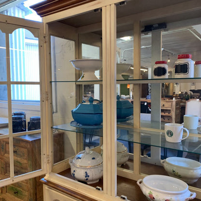 Glass-fronted cabinet displaying various kitchen items including a blue pot and a Starbucks mug.