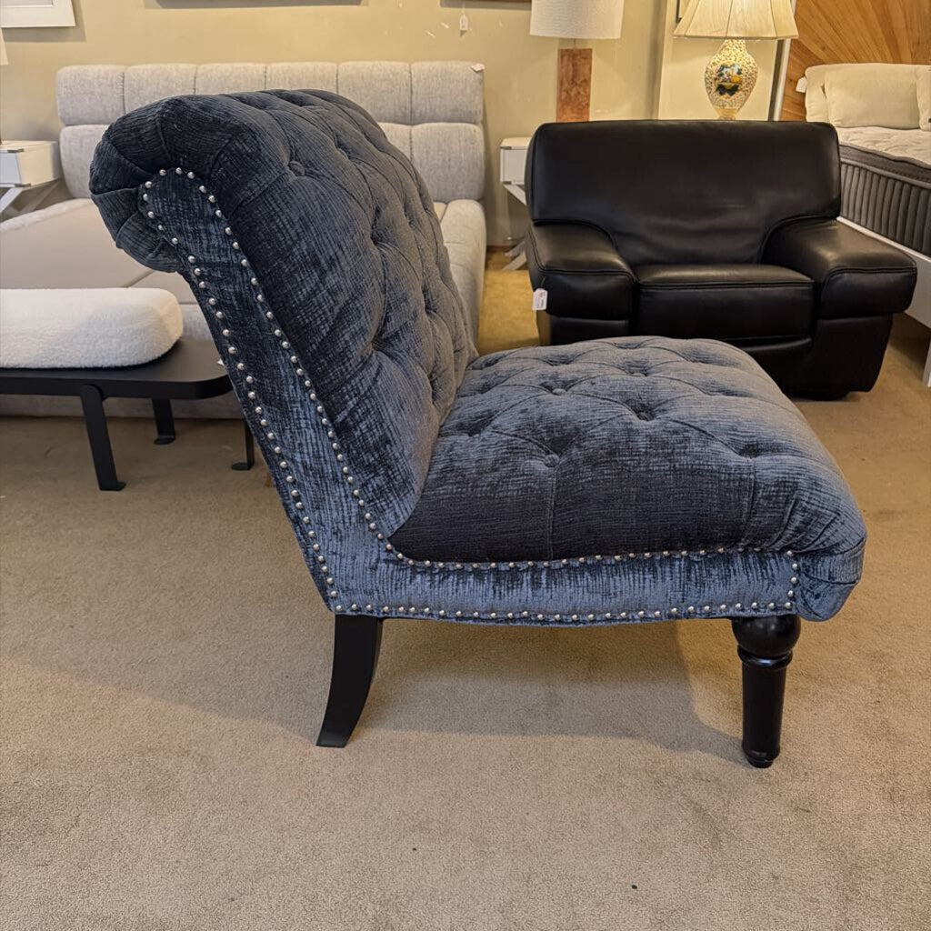 Blue tufted armchair with nailhead trim in a showroom setting