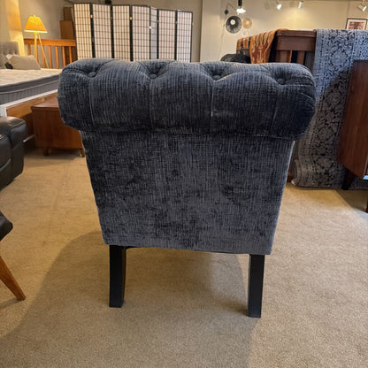 Blue tufted chair in a room with furniture and decor.