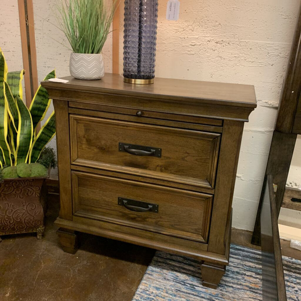 Wooden nightstand with two drawers in a room setting with plants and decor.