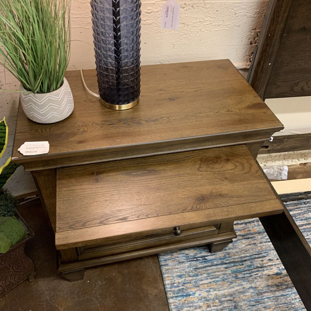 Wooden side table with a lamp and plant in a store setting