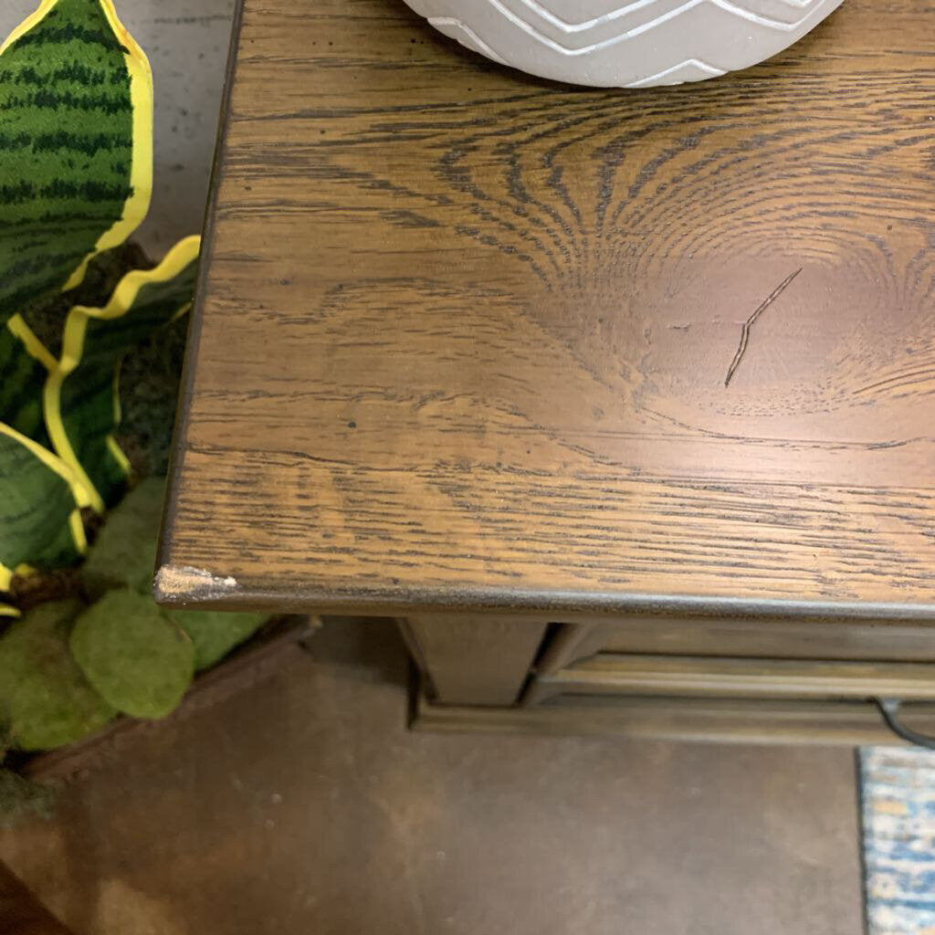 Wooden surface with a plant and a white object in the background