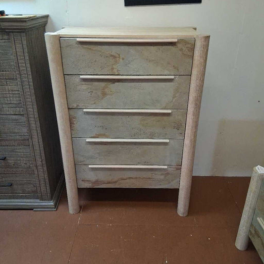 Wooden dresser with four drawers on a brown floor.
