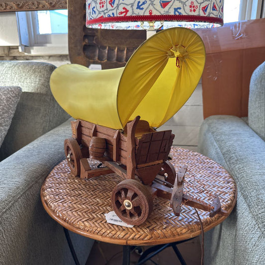 Model of a covered wagon with a yellow sail on a woven table