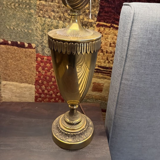 Decorative gold lamp on a surface with a textured wall and gray chair in the background