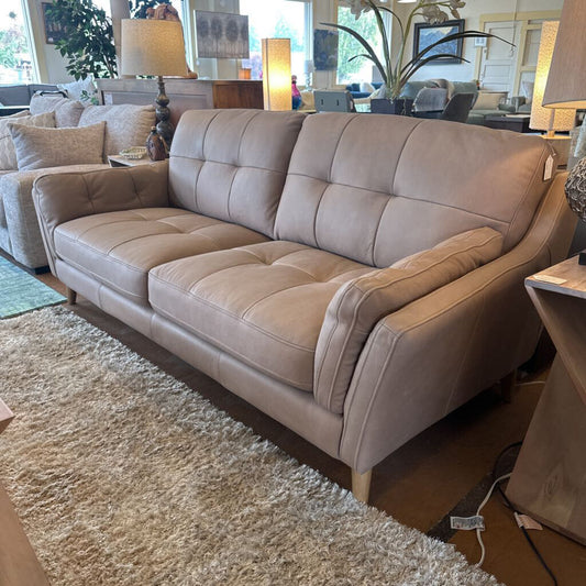 Beige sectional sofa in a living room setting with decor elements.
