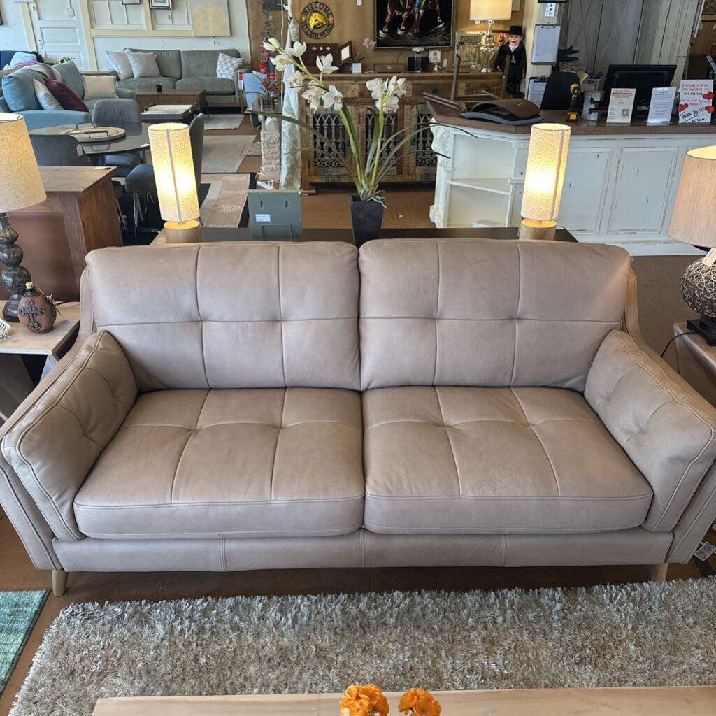 Beige sectional sofa in a showroom setting with lamps and decor.