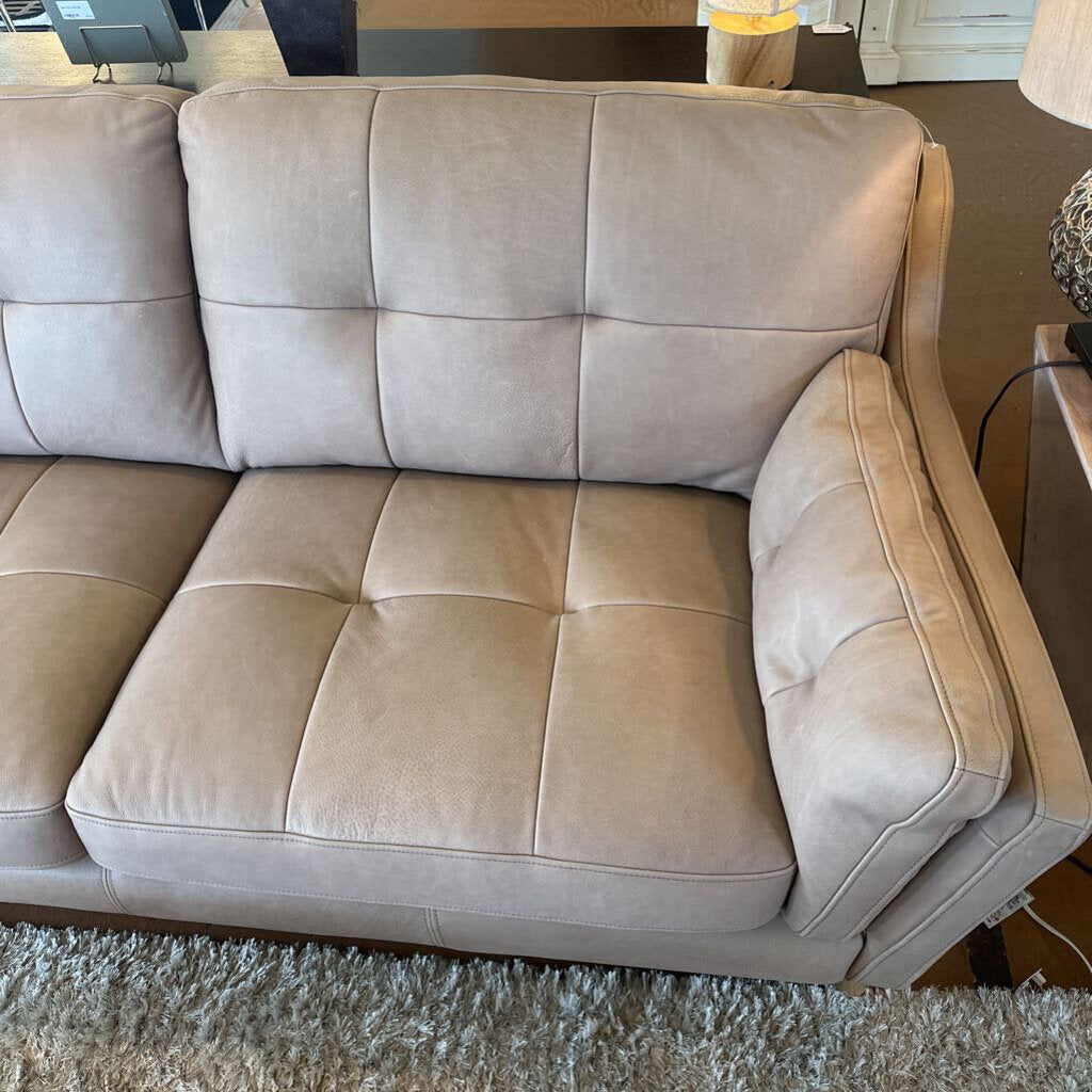 Beige sofa in a room with a lamp and table in the background
