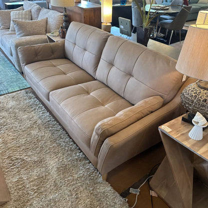 Beige sectional sofa in a living room setting with a lamp and rug.