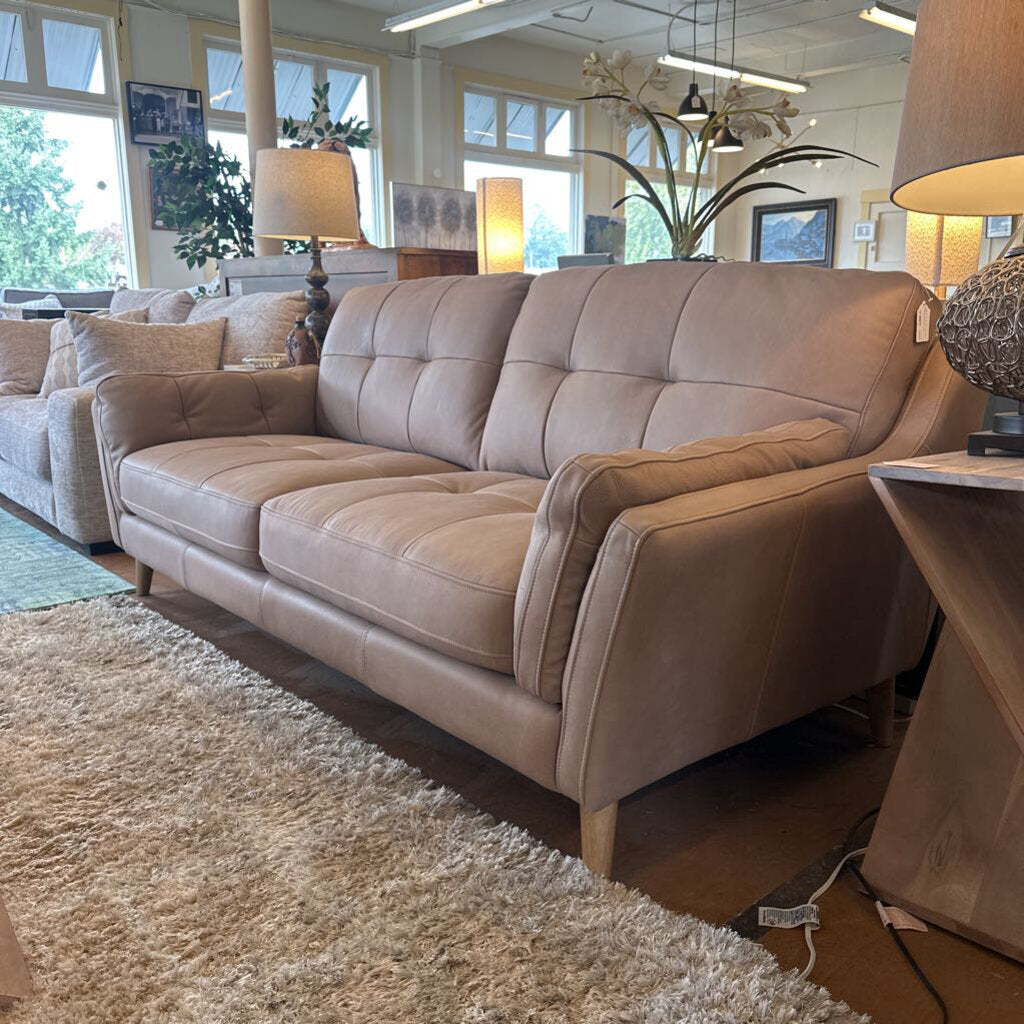 Beige sofa in a room with large windows and decorative elements.