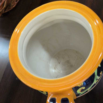 Close-up of a ceramic jar with a yellow lid on a dark surface