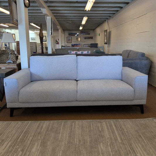 Gray sofa in a showroom with other furniture and decor items.