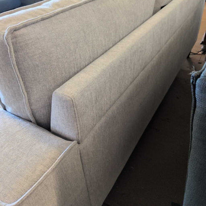 Beige sofa with a focus on the armrest and backrest.