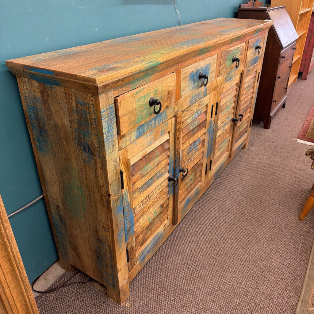 Wooden cabinet with multicolored finish against a blue wall.